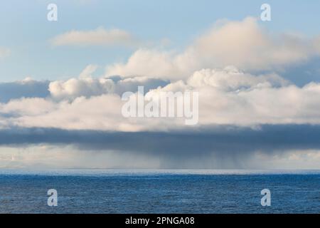 Tief liegende Regenwolken treiben über das offene Wasser des blauen Atlantischen Ozeans Stockfoto