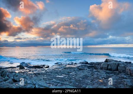 Tief liegende Regenwolken, die über das offene Wasser des blauen Atlantiks bei Sonnenuntergang driften, mit orangefarbenem, wolkigen Himmel, Nordwestküste Schottlands Stockfoto