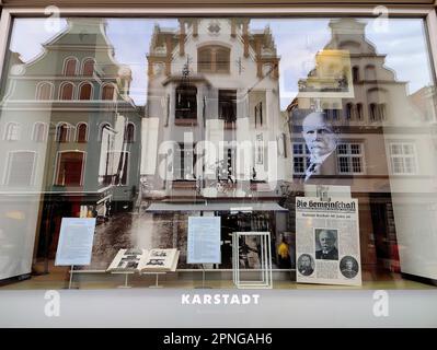 Blick in das Schaufenster mit Reflexionen von Giebelhäusern, dem Flagship Store von Karstadt, Wismar, Mecklenburg-Vorpommern, Deutschland Stockfoto