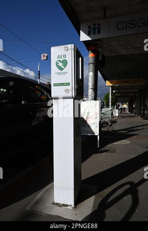 Öffentlich zugänglicher automatisierter externer Defibrillator (AED) in einer Box am Straßenrand auf dem Fußweg vor den Geschäften vor Ort Stockfoto