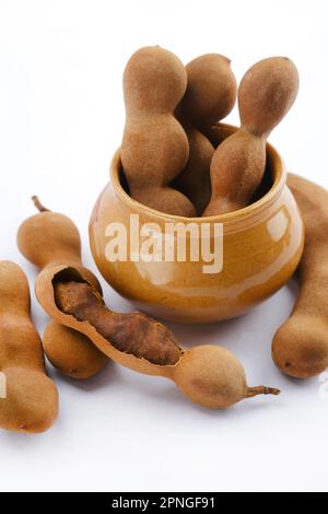 Frische, köstliche, reife Tamarinden, Tamarinden mit braunem Fruchtfleisch und grünen Blättern. Stockfoto