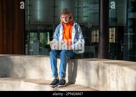 Fokussierter Student, der an einem Forschungsprojekt arbeitet, auf Zementstufen in der Nähe der Universität. Stockfoto
