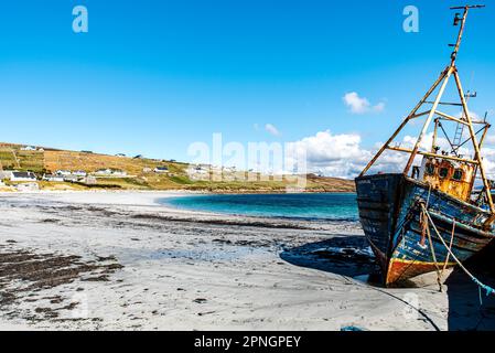 Verlassenes Boot oder Fischertrawler auf der Insel Arranmore, Republik Irland. Rostiges Schiff oder schräges Schiff, das an einem weißen Strand in der Grafschaft Donegal gestrandet ist Stockfoto