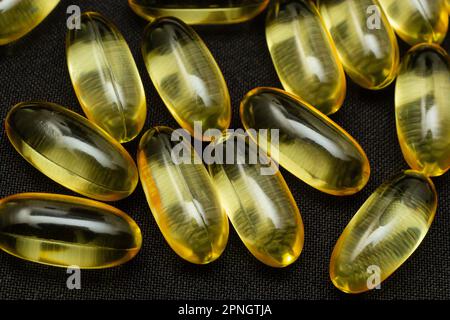 Makro-Nahaufnahme der Omega 3-Gelkapsel auf reflektierendem schwarzem Hintergrund. Stockfoto