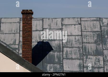 Metalldach eines Einzelhauses und Schornstein am Himmel, Dachziegel aus Metall, Dachrinnen. Stockfoto