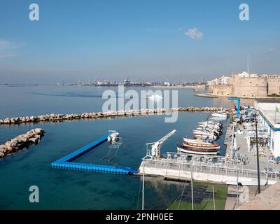 TARANTO, ITALIEN - 29. OKTOBER 2021: Hafenlandschaft mit Kränen und Castello Aragonese Festung im Hintergrund in Taranto, Italien Stockfoto