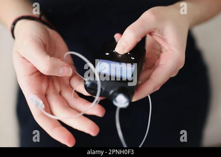 Frau, die ihre Insulinpumpe in den Händen hält Stockfoto