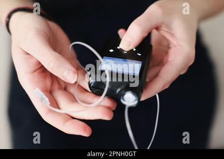 Frau, die ihre Insulinpumpe in den Händen hält Stockfoto