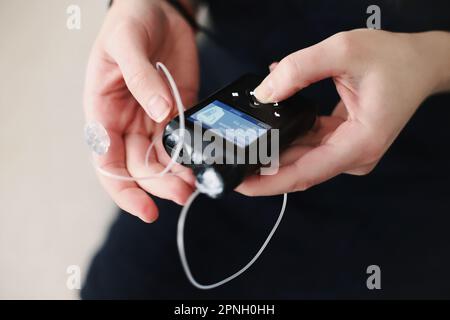 Frau, die ihre Insulinpumpe in den Händen hält Stockfoto