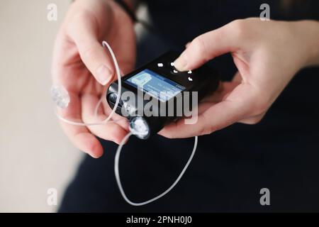 Frau, die ihre Insulinpumpe in den Händen hält Stockfoto