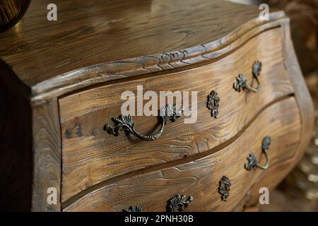 Vintage-Nahaufnahme mit gebogener Kommode. Geschmiedete Griffe. Stockfoto