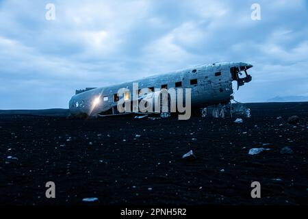 Island - August 2021: Lichteffekt in der Nacht des alten abgestürzten Flugzeugabsturzes, das an einem abgelegenen schwarzen Sandstrand in Island aufgegeben wurde Stockfoto