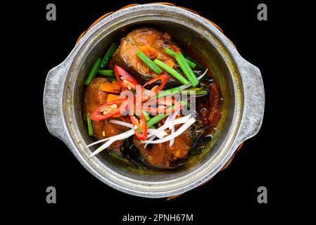 Vietnamesischer gebratener Makrelenfisch mit Sauce auf schwarzem Hintergrund Stockfoto