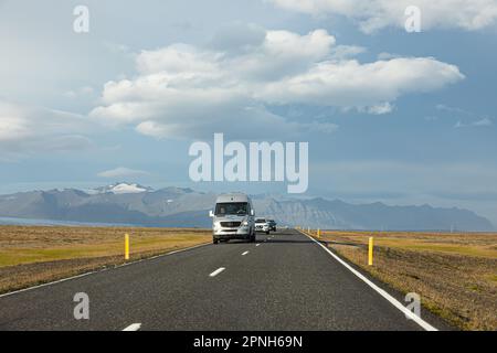 Island - August 2021: suv-Autos auf einer isländischen Straße mit wunderschöner grüner Landschaft und Bergen im Hintergrund Stockfoto