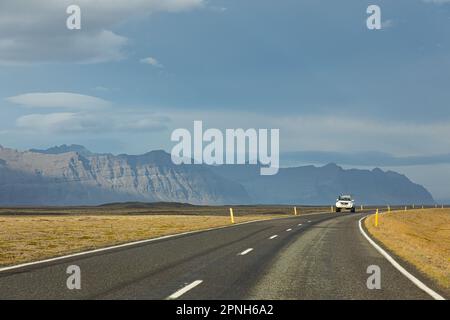 Island - August 2021: suv-Autos auf einer isländischen Straße mit wunderschöner grüner Landschaft und Bergen im Hintergrund Stockfoto