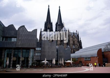 Kölner Kathdreal hinter dem Museum Ludwig am 6. April 2023 in Köln. Der Kölner Dom ist eine Kirche im gotischen Stil in Nordrhein-Westfalen und gehört zur katholischen Kirche. Es ist der Sitz des Erzbischofs von Köln und der Verwaltung der Erzdiözese von Köln. Es ist das meistbesuchte Wahrzeichen Deutschlands und zieht durchschnittlich 20.000 Menschen pro Tag an. Mit 157m or515 m ist es die höchste Kirche mit Zwillingsspinnen der Welt, die zweithöchste Kirche in Europa nach Ulm Minster und die drittgrößte Kirche aller Art in der Welt. Stockfoto