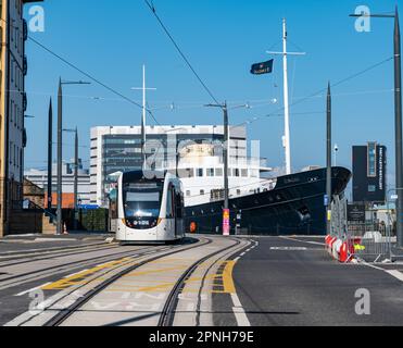 Leith, Edinburgh, Schottland, Großbritannien, 19. April 2023. Straßenbahnen nach Newhaven: Die ersten Straßenbahnen, die tagsüber auf der verlängerten Straßenbahnlinie verkehren, begannen heute, die Strecke zu testen. Abbildung: Eine Straßenbahn fährt am "Fingal Edinburgh" vorbei, einem luxuriösen schwimmenden Hotel. Kredit: Sally Anderson/Alamy Live News Stockfoto