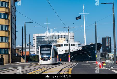 Leith, Edinburgh, Schottland, Großbritannien, 19. April 2023. Straßenbahnen nach Newhaven: Die ersten Straßenbahnen, die tagsüber auf der verlängerten Straßenbahnlinie verkehren, begannen heute, die Strecke zu testen. Abbildung: Eine Straßenbahn fährt am "Fingal Edinburgh" vorbei, einem luxuriösen schwimmenden Hotel. Kredit: Sally Anderson/Alamy Live News Stockfoto