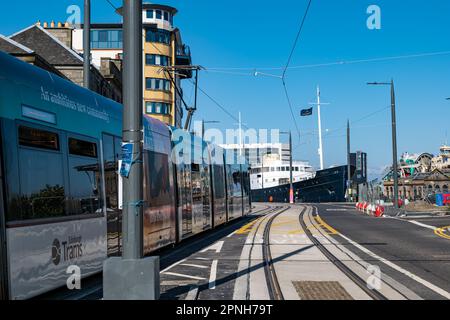 Leith, Edinburgh, Schottland, Großbritannien, 19. April 2023. Straßenbahnen nach Newhaven: Die ersten Straßenbahnen, die tagsüber auf der verlängerten Straßenbahnlinie verkehren, begannen heute, die Strecke zu testen. Abbildung: Eine Straßenbahn fährt am "Fingal Edinburgh" vorbei, einem luxuriösen schwimmenden Hotel. Kredit: Sally Anderson/Alamy Live News Stockfoto