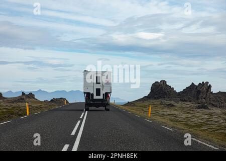 Island - August 2021: Karawane auf einer Straße in der isländischen Landschaft mit wunderschöner grüner Landschaft und Bergen im Hintergrund Stockfoto