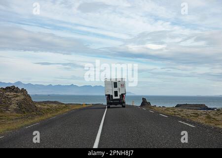 Island - August 2021: Karawane auf einer Straße in der isländischen Landschaft mit wunderschöner grüner Landschaft und Bergen im Hintergrund Stockfoto