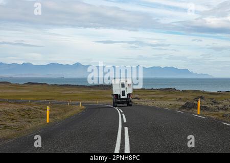 Island - August 2021: Karawane auf einer Straße in der isländischen Landschaft mit wunderschöner grüner Landschaft und Bergen im Hintergrund Stockfoto