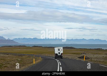 Island - August 2021: Karawane auf einer Straße in der isländischen Landschaft mit wunderschöner grüner Landschaft und Bergen im Hintergrund Stockfoto