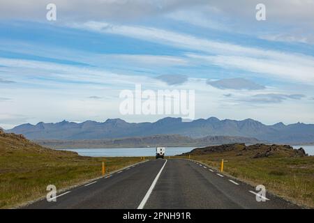 Island - August 2021: Karawane auf einer Straße in der isländischen Landschaft mit wunderschöner grüner Landschaft und Bergen im Hintergrund Stockfoto