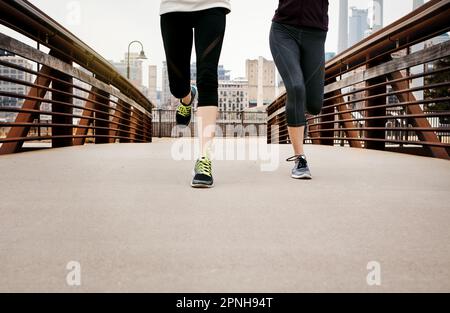 Auf dem Weg zur Ziellinie. Zwei nicht wiedererkennbare junge Frauen laufen durch die Stadt. Stockfoto