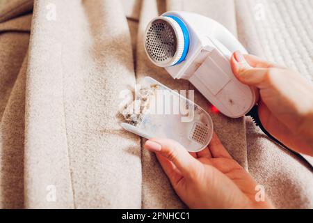 Flusenentferner nach der Rasur von Flusen am Kleidungsstück reinigen. Nehmen Sie den Behälter mit abgeschnittenen Pillen und Schmutz ab. Pflege des Geräts Stockfoto
