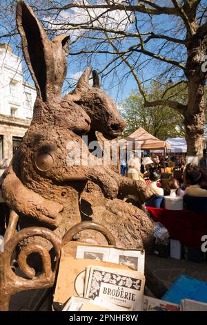 Haar und Minotaurus-Statue mit Blick auf den Cheltenham Antiques and Vintage Market, Straßenmarkt am Samstag auf der Promenade im Cheltenham Spa. Straßenverkäufer und Kleiderstände in der Nähe der georgianischen Terrassen von Stadthäusern in der Stadt Gloucestershire. UK. (134) Stockfoto