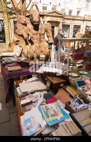 Haar und Minotaurus-Statue mit Blick auf den Cheltenham Antiques and Vintage Market, Straßenmarkt am Samstag auf der Promenade im Cheltenham Spa. Straßenverkäufer und Kleiderstände in der Nähe der georgianischen Terrassen von Stadthäusern in der Stadt Gloucestershire. UK. (134) Stockfoto