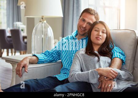 Das perfekte Bild des ehelichen Glücks. Ein glückliches junges Paar, das sich zu Hause auf dem Sofa entspannt. Stockfoto