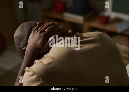 Ein afroamerikanischer depressiver Mann, der Probleme hat, er sitzt allein in seinem Zimmer Stockfoto