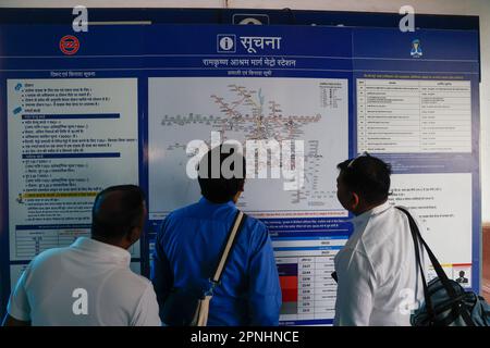 Drei Männer schauen auf die Karte der öffentlichen Verkehrsmittel an der Ramakrishna Ashram Marg Metro Station in Delhi, Indien Stockfoto