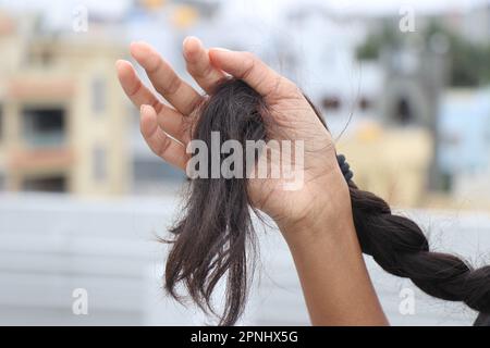 Geflochtenes weibliches Haar mit der Haarspitze in der Hand. Schönes, gesundes, natürliches weibliches Haar Stockfoto