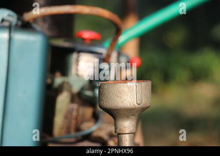 Nahaufnahme des Pumpenrohrs einer Kreiselwasserpumpe mit Blick auf den Dieselmotorsatz im Hintergrund Stockfoto