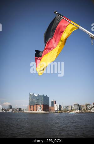 Hamburg, Deutschland. 17. April 2023. Eine deutsche Flagge fliegt am Heck eines Ausflugsschiffs im Hamburger Hafen über der Elbphilharmonie. Kredit: Christian Charisius/dpa/Alamy Live News Stockfoto