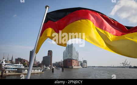 Hamburg, Deutschland. 17. April 2023. Eine deutsche Flagge fliegt am Heck eines Ausflugsschiffs im Hamburger Hafen über der Elbphilharmonie. Kredit: Christian Charisius/dpa/Alamy Live News Stockfoto