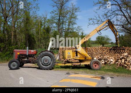 Alter Landwirtschaftstraktor mit Kran zum Laden von Holzstamm Stockfoto