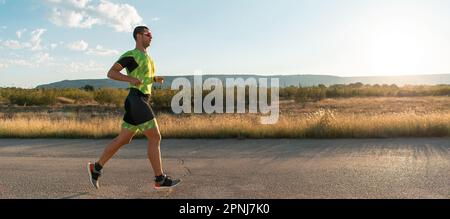 Triathlet in professioneller Ausrüstung, der früh am Morgen läuft, sich auf einen Marathon vorbereitet, sich sportlich engagiert und bereit ist, sich den Herausforderungen von zu stellen Stockfoto