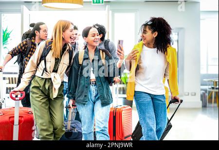 Gemischte Freunde kommen in der Hotellobby mit Koffern an - Reiseurlaubskonzept mit jungen Leuten, die Spaß haben Stockfoto