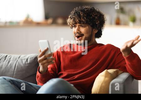 Oh Nein Schockierter Indischer Mann, Der Zu Hause Eine Schlechte Nachricht Auf Dem Smartphone Liest Stockfoto