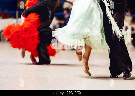 Paare, die wiener Walzer tanzen, im Turnierball tanzen, Frau trägt lila und rotes Kleid, Mann im schwarzen Anzug Stockfoto