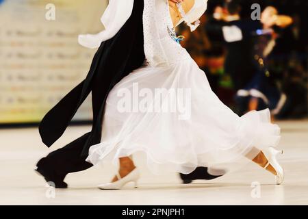 Partner tanzt Tango im Tanzsaal, Frau trägt weißes Kleid und schwarzen Schwanzanzug auf Mann Stockfoto