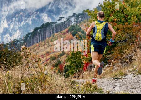 Rückwärtiger Skyrunner mit Wanderstöcken in der Hand und Rucksack für den Bergmarathon, Skyrunning World Series Stockfoto