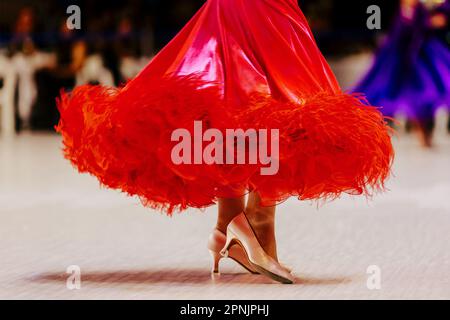 Rotes Ballkleid und Füße im Schuh einer Tänzerin auf Parkett Stockfoto
