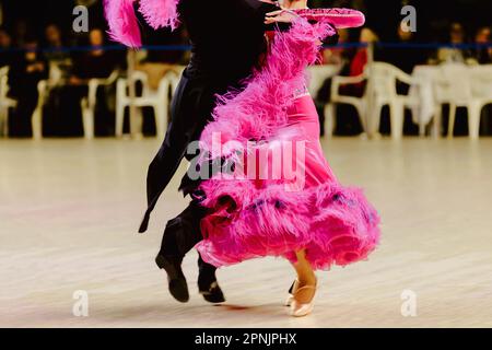 Ein Paar tanzt Foxtrott im Turnierball, die Frau trägt ein rosa Kleid und einen schwarzen Schwanzanzug Stockfoto