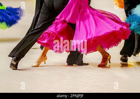 Nahaufnahme eines teils pinkfarbenen Ballkleides und eines schwarzen männlichen Anzugs auf der Tanzfläche Stockfoto