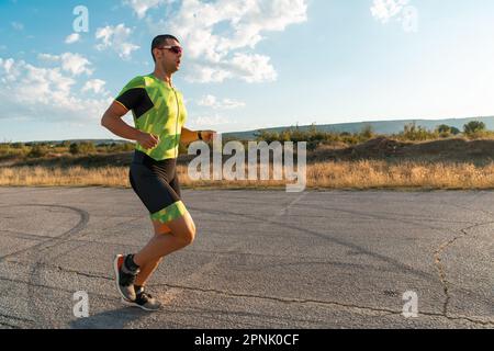 Triathlet in professioneller Ausrüstung, der früh am Morgen läuft, sich auf einen Marathon vorbereitet, sich sportlich engagiert und bereit ist, sich den Herausforderungen von zu stellen Stockfoto